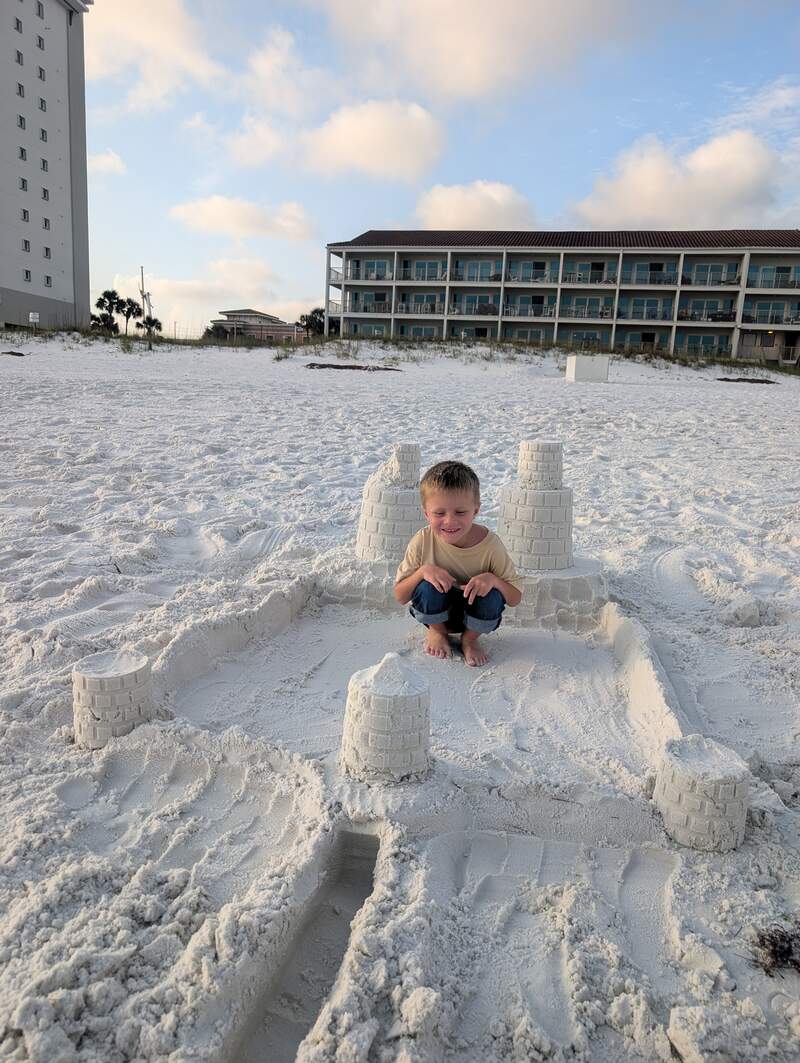 Noah in a sand castle on the beach